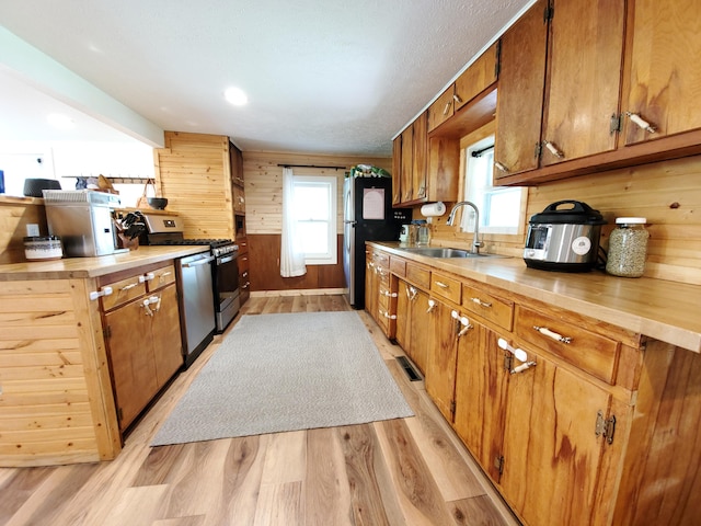 1010 Pine St, Cabool, MO 65689 - kitchen with stainless steel gas range oven, light wood-style flooring, wooden walls, wood counters, and brown cabinetry