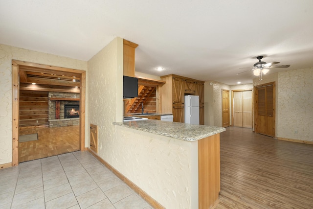 247 S Jefferson St, Walnut Grove, MO 65770 - kitchen with white appliances, baseboards, ceiling fan, a lit fireplace, and a peninsula