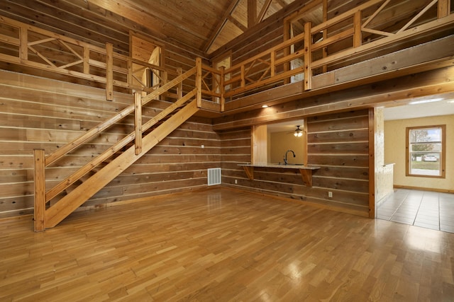 247 S Jefferson St, Walnut Grove, MO 65770 - unfurnished living room featuring wooden walls, wood finished floors, stairs, lofted ceiling, and a sink