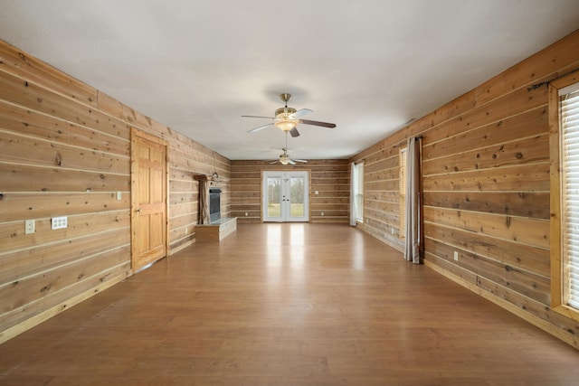 247 S Jefferson St, Walnut Grove, MO 65770 - unfurnished living room with wooden walls, a ceiling fan, wood finished floors, and french doors