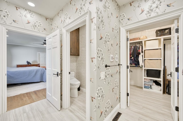 3596 E Montrose Ct, Springfield, MO 65809 - ensuite bathroom with wallpapered walls, toilet, baseboards, wood finished floors, and ceiling fan