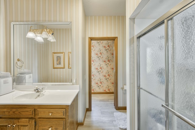 3596 E Montrose Ct, Springfield, MO 65809 - bathroom featuring wallpapered walls, vanity, wood finished floors, a shower with door, and baseboards