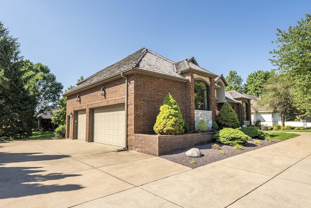 3596 E Montrose Ct, Springfield, MO 65809 - view of home's exterior with brick siding, concrete driveway, a garage, and a high end roof
