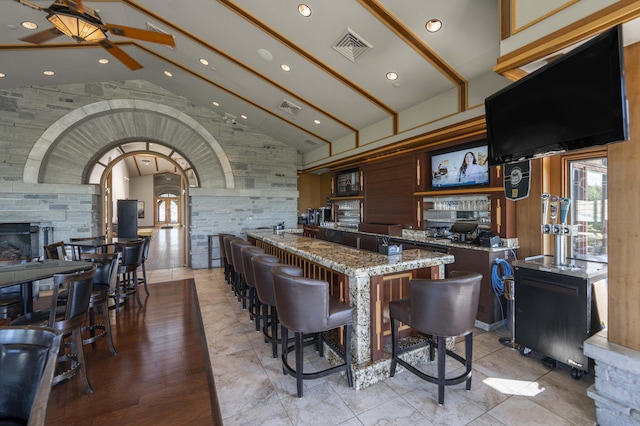 3596 E Montrose Ct, Springfield, MO 65809 - kitchen featuring beamed ceiling, a center island, stone countertops, a ceiling fan, and a kitchen bar