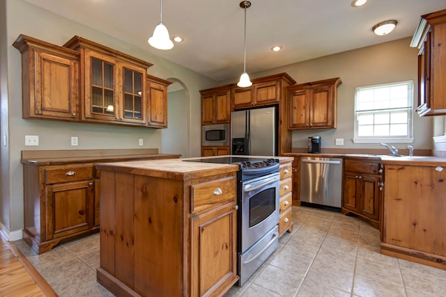 1214 Evington Ct, Springfield, MO 65803 - kitchen with stainless steel appliances, a kitchen island, brown cabinetry, decorative light fixtures, and a sink