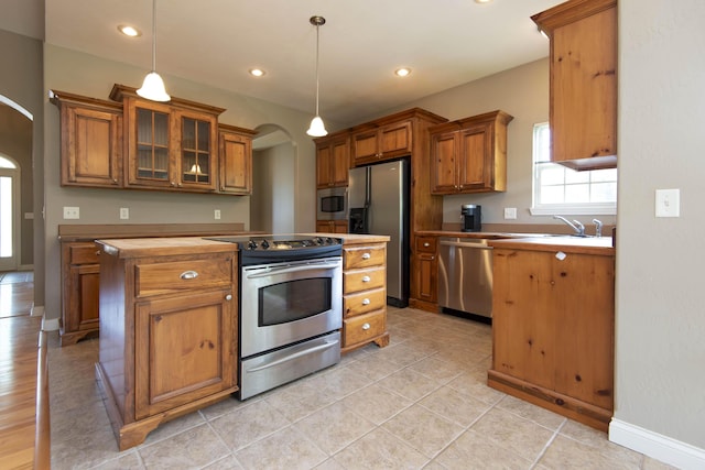 1214 Evington Ct, Springfield, MO 65803 - kitchen featuring appliances with stainless steel finishes, brown cabinetry, arched walkways, decorative light fixtures, and recessed lighting
