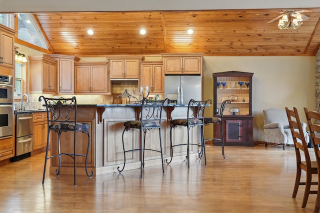 1041 Skyview Dr, Branson, MO 65616 - kitchen with appliances with stainless steel finishes, wood ceiling, a kitchen bar, light wood-style flooring, and backsplash