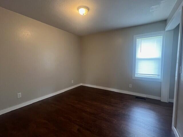 1217 Blair St, Cabool, MO 65689 - spare room featuring dark wood-type flooring and baseboards
