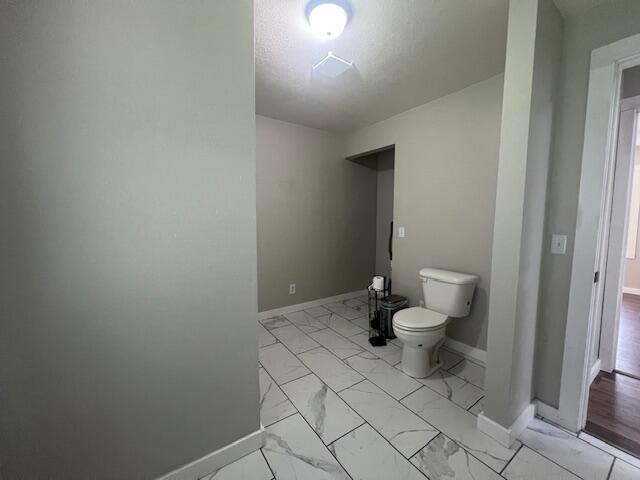 1217 Blair St, Cabool, MO 65689 - bathroom with marble look tiles, toilet, and baseboards