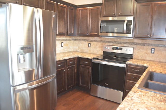 532 Holiday St, Highlandville, MO 65669 - kitchen with appliances with stainless steel finishes, dark wood-type flooring, backsplash, and dark brown cabinets