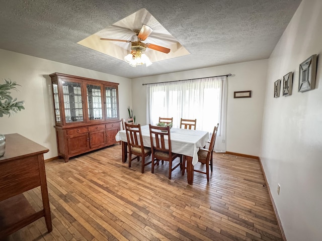 5350 E Farm Road 168, Rogersville, MO 65742 - dining room featuring a textured ceiling, light wood-type flooring, baseboards, ceiling fan, and a tray ceiling
