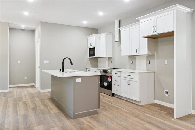 1239 W Arlington Ct, Springfield, MO 65803 - kitchen featuring a sink, stainless steel electric range, an island with sink, light wood-type flooring, and black microwave
