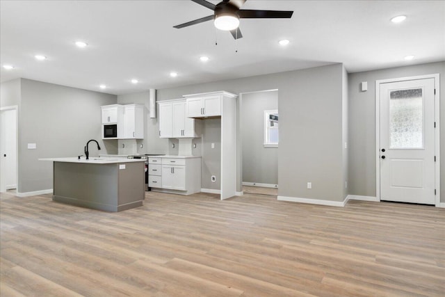 1239 W Arlington Ct, Springfield, MO 65803 - kitchen featuring ceiling fan, black microwave, white cabinetry, an island with sink, and baseboards