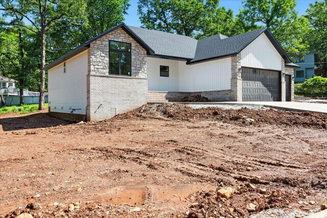 1239 W Arlington Ct, Springfield, MO 65803 - view of front of house with an attached garage, driveway, brick siding, a shingled roof, and stone siding