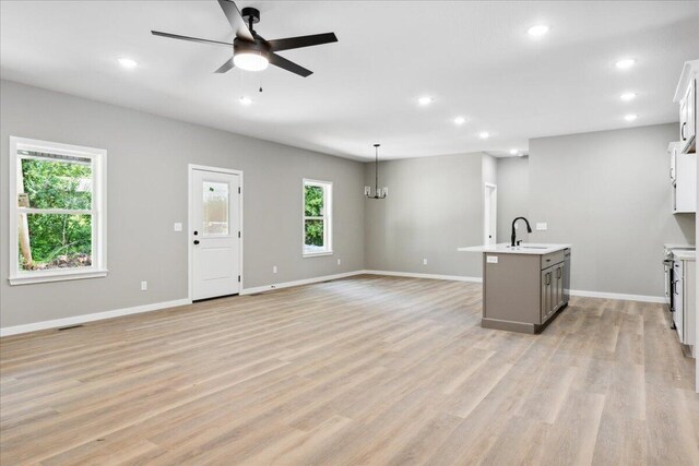1239 W Arlington Ct, Springfield, MO 65803 - unfurnished living room with a ceiling fan, recessed lighting, baseboards, light wood-style flooring, and a sink