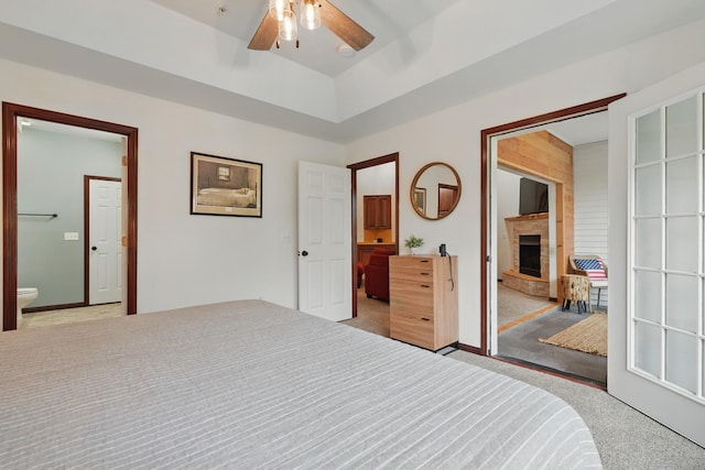 235 Lower Emerald Bay Cir Unit C-6, Hollister, MO 65672 - bedroom featuring ensuite bathroom, light carpet, a fireplace with raised hearth, baseboards, and a ceiling fan