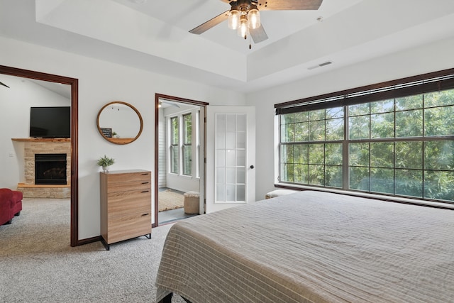 235 Lower Emerald Bay Cir Unit C-6, Hollister, MO 65672 - bedroom with light colored carpet, a raised ceiling, a fireplace with raised hearth, ceiling fan, and baseboards