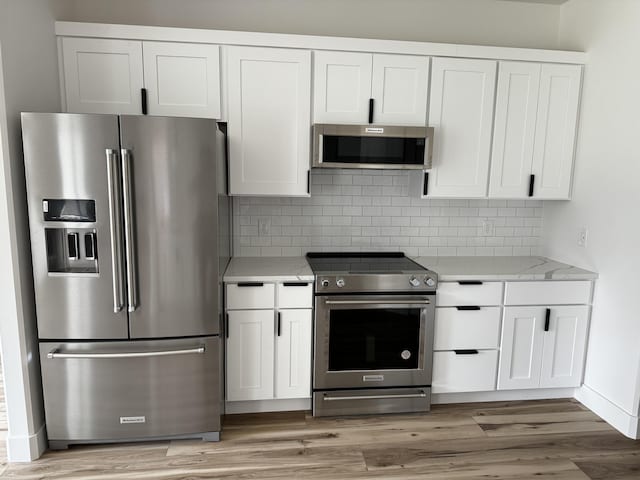 2048 N Sun Valley Dr, Springfield, MO 65802 - kitchen with stainless steel appliances, white cabinets, decorative backsplash, and light wood-type flooring