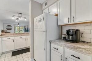 151 Highland Dr Unit 3, Branson, MO 65616 - kitchen with freestanding refrigerator, white cabinetry, backsplash, and light tile patterned floors