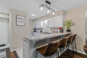 151 Highland Dr Unit 3, Branson, MO 65616 - kitchen with baseboards, a breakfast bar, and white cabinets