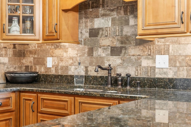 130 Royal Vista Dr Unit 601, Branson, MO 65616 - kitchen featuring a sink, tasteful backsplash, glass insert cabinets, dark stone counters, and brown cabinets