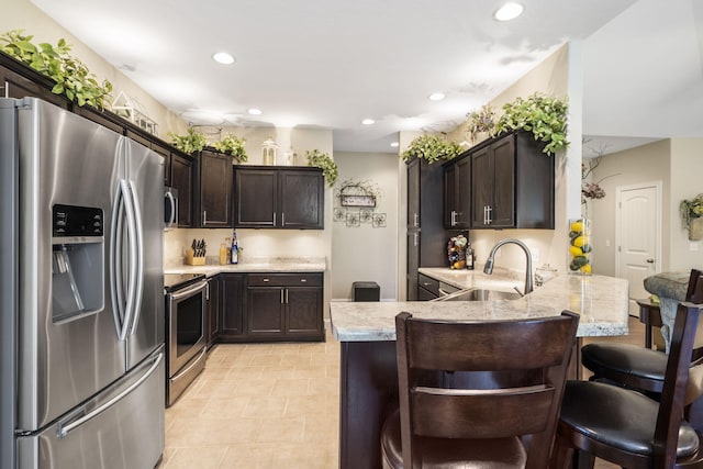 94 W Pine Ln, Reeds Spring, MO 65737 - kitchen featuring appliances with stainless steel finishes, a peninsula, dark brown cabinets, recessed lighting, and a kitchen bar