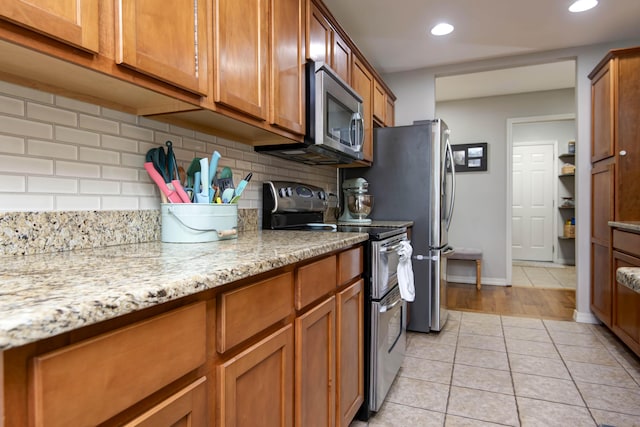 326 Country Bluff Dr, Branson, MO 65616 - kitchen with stainless steel appliances, brown cabinets, light tile patterned floors, backsplash, and recessed lighting