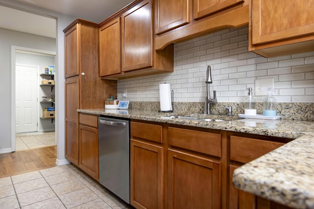 326 Country Bluff Dr, Branson, MO 65616 - kitchen with stainless steel dishwasher, a sink, brown cabinetry, backsplash, and light tile patterned floors