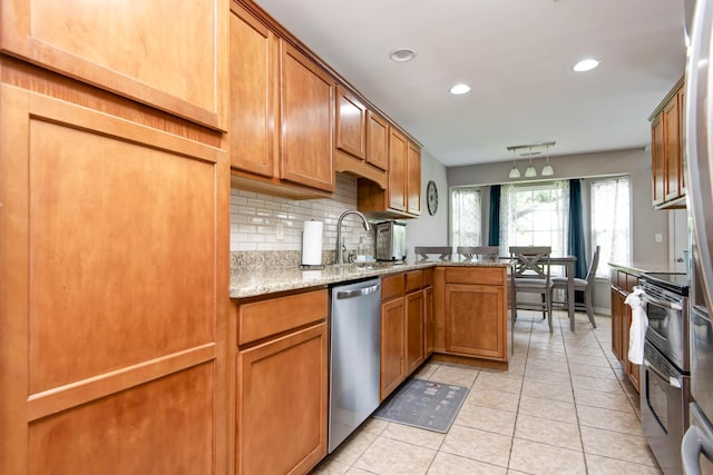 326 Country Bluff Dr, Branson, MO 65616 - kitchen with appliances with stainless steel finishes, a sink, brown cabinets, light tile patterned floors, and tasteful backsplash