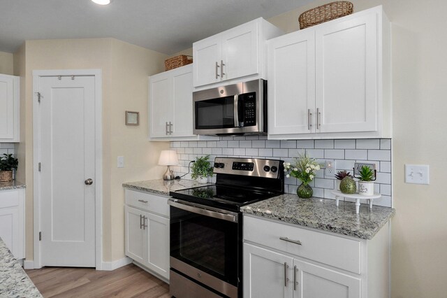 1132 E Lakota St, Nixa, MO 65714 - kitchen with stainless steel appliances, light wood finished floors, white cabinets, backsplash, and light stone countertops