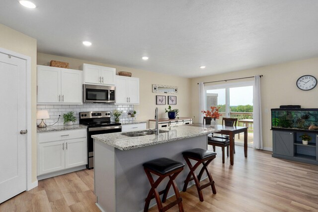 1132 E Lakota St, Nixa, MO 65714 - kitchen featuring appliances with stainless steel finishes, a sink, a kitchen breakfast bar, light wood finished floors, and white cabinets