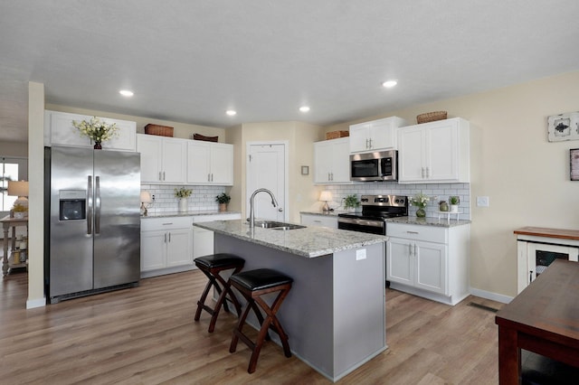1132 E Lakota St, Nixa, MO 65714 - kitchen featuring stainless steel appliances, a sink, light wood-type flooring, decorative backsplash, and recessed lighting