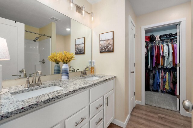 1132 E Lakota St, Nixa, MO 65714 - full bathroom with wood finished floors, double vanity, a shower, baseboards, and a spacious closet