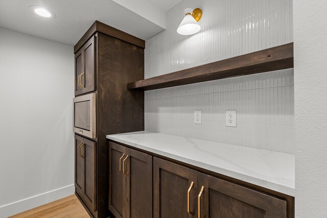 5567 E Wild Horse Dr, Springfield, MO 65802 - kitchen with open shelves, dark brown cabinetry, light stone countertops, light wood-style floors, and baseboards