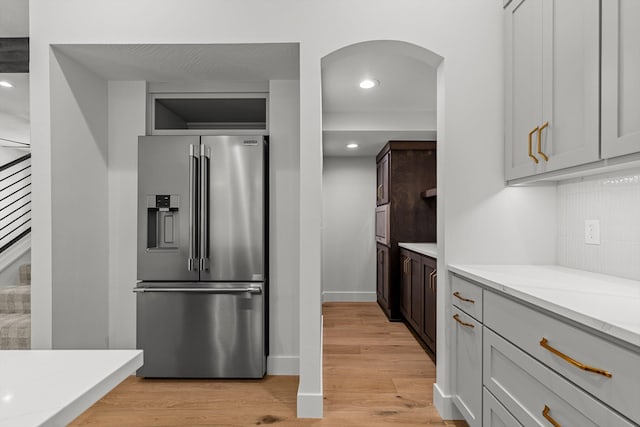 5567 E Wild Horse Dr, Springfield, MO 65802 - kitchen featuring high end fridge, arched walkways, light wood-style floors, decorative backsplash, and recessed lighting