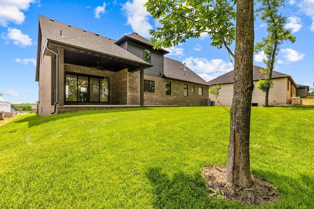 5567 E Wild Horse Dr, Springfield, MO 65802 - rear view of property featuring a ceiling fan, a lawn, brick siding, and a shingled roof