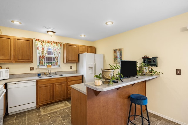 120 Deer Run Rd, Branson, MO 65616 - kitchen featuring white appliances, a sink, a breakfast bar, brown cabinetry, and light countertops