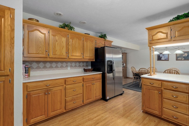 5473 N State Highway 125, Strafford, MO 65757 - kitchen featuring stainless steel refrigerator with ice dispenser, light countertops, tasteful backsplash, light wood-style flooring, and brown cabinets