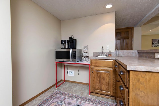 5052 E Cherry Pl, Springfield, MO 65809 - kitchen featuring stainless steel microwave, a sink, baseboards, brown cabinetry, and light countertops