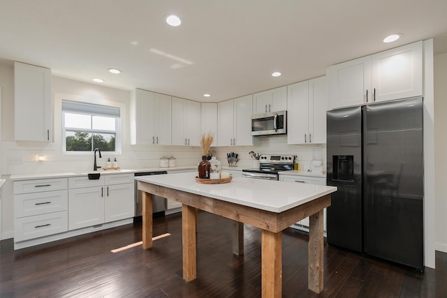 777 S Elm St, Marshfield, MO 65706 - kitchen with stainless steel appliances, a kitchen breakfast bar, light countertops, dark wood-style flooring, and white cabinets