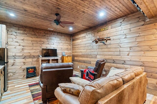 6 Glory Ln, Blue Eye, MO 65611 - living room with wood ceiling, a ceiling fan, a wood stove, wood finished floors, and wood walls