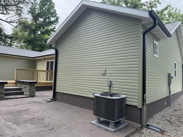 1922 S Village Ln, Bolivar, MO 65613 - view of property exterior featuring a wooden deck, cooling unit, a patio, and roof with shingles