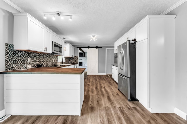 32 State Road F, Buffalo, MO 65622 - kitchen with stainless steel appliances, a barn door, butcher block countertops, a peninsula, and a sink