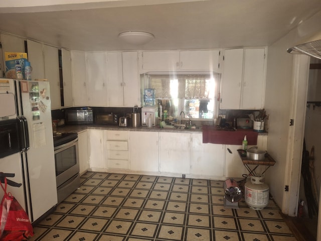 1224 Columbus St, West Plains, MO 65775 - kitchen featuring electric stove, white cabinets, freestanding refrigerator, black microwave, and light floors