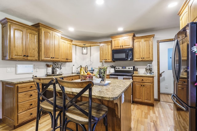 1427 W Missouri St, Buffalo, MO 65622 - kitchen with black microwave, stainless steel electric range oven, freestanding refrigerator, light wood-style floors, and a kitchen bar