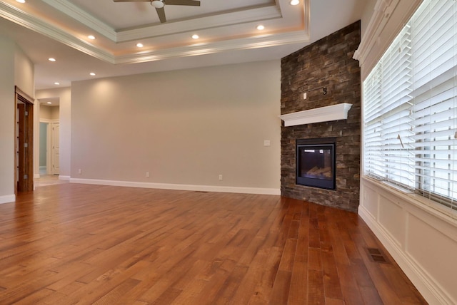 1189 N Cedar Ridge Ave, Springfield, MO 65802 - unfurnished living room with a tray ceiling, ceiling fan, ornamental molding, wood finished floors, and a stone fireplace