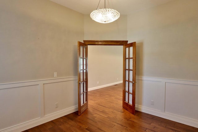 1189 N Cedar Ridge Ave, Springfield, MO 65802 - empty room featuring a decorative wall, a chandelier, wood finished floors, a wainscoted wall, and french doors
