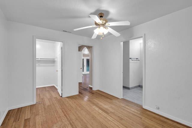 875-883 State Route T, West Plains, MO 65775 - unfurnished bedroom with a walk in closet, light wood-type flooring, a closet, arched walkways, and baseboards