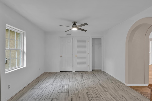 875-883 State Route T, West Plains, MO 65775 - unfurnished bedroom featuring arched walkways, wood finish floors, baseboards, and a ceiling fan