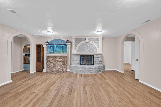 875-883 State Route T, West Plains, MO 65775 - unfurnished living room featuring wood-type flooring, arched walkways, baseboards, and a fireplace